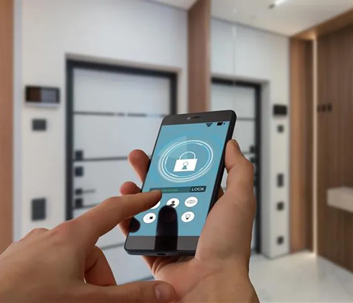 A hand holds a smartphone displaying a smart lock app interface, with blurred background of modern doors.